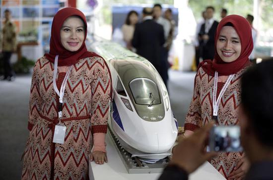  2016年1月21日，在印度尼西亚西爪哇省瓦利尼，两名印尼妇女在开工仪式上与高铁列车模型合影。新华社/美联